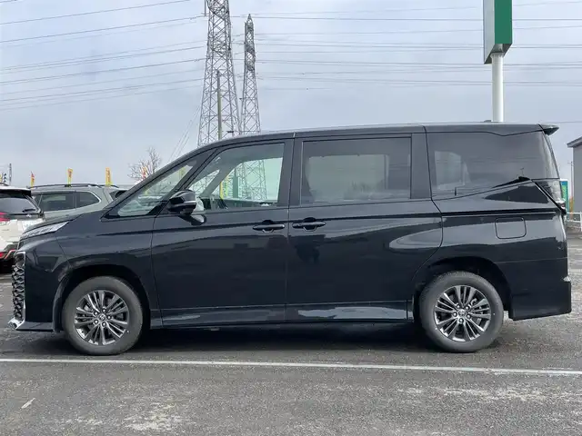 トヨタ ヴォクシー ハイブリッド S－G 道央・札幌 2025(令7)年 1.1万km グリッターブラックガラスフレーク ４WD/寒冷地仕様/純正ディスプレイオーディオ（ナビ付）/AM/FM/BT/トヨタセーフティセンス/プリクラッシュセーフティ/横滑り防止装置/レーダークルーズコントロール/レーンキープアシスト/パーキングアシスト/プロアクティブドライビングアシスト/パーキングサポートブレーキ/ロードサインアシスト/クリアランスソナー/バックカメラ/ビルトインETC2.0/EVMODE/DRIVEMODE切替/ワイパーデアイサー/片側パワースライドドア/革巻きステアリング/ステアリングリモコン/電動パーキング/ブレーキホールド/プッシュスタート/スマートキー/LEDヘッドライト/オートライト/オートハイビーム/ヘッドライトレベライザー/電動格納ミラー/ウィンカーミラー/純正フロアマット/レンタカー登録