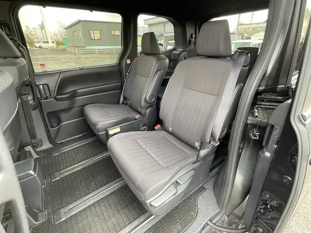 トヨタ ヴォクシー ハイブリッド S－G 道央・札幌 2025(令7)年 1.1万km グリッターブラックガラスフレーク ４WD/寒冷地仕様/純正ディスプレイオーディオ（ナビ付）/AM/FM/BT/トヨタセーフティセンス/プリクラッシュセーフティ/横滑り防止装置/レーダークルーズコントロール/レーンキープアシスト/パーキングアシスト/プロアクティブドライビングアシスト/パーキングサポートブレーキ/ロードサインアシスト/クリアランスソナー/バックカメラ/ビルトインETC2.0/EVMODE/DRIVEMODE切替/ワイパーデアイサー/片側パワースライドドア/革巻きステアリング/ステアリングリモコン/電動パーキング/ブレーキホールド/プッシュスタート/スマートキー/LEDヘッドライト/オートライト/オートハイビーム/ヘッドライトレベライザー/電動格納ミラー/ウィンカーミラー/純正フロアマット/レンタカー登録