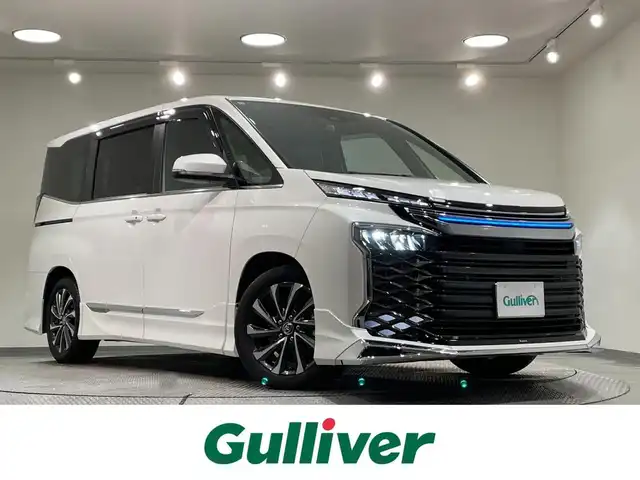 トヨタ ヴォクシー ハイブリッド S－Z 愛知県 2024(令6)年 0.9万km ホワイトパールクリスタルシャイン モデリスタエアロ　F/S/R/サイドステップ/純正10.5インチナビ/（フルセグTV/AM/FM/Bluetooth）/両側パワースライドドア/レーダークルーズコントロール/１００V電源/ビルトインETC2.0/シートヒーター/バックカメラ/前後ドライブレコーダー/ステアリングヒーター/コーナーセンサー/レーンキープアシスト/パーキングアシスト/HDMI接続/プッシュスタート/スマートキー/スペアキー/純正フロアマット/純正17インチアルミホイール/オートライト