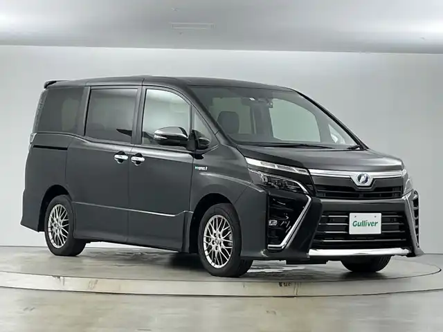 トヨタ ヴォクシー ハイブリッド ZS 煌Ⅱ 愛知県 2019(平31)年 6万km イナズマスパーキングブラックガラスフレーク 禁煙車/純正10インチナビ/（CD/DVD/Bluetooth/フルセグTV/HDMI/USB)/バックカメラ/フリップダウンモニター/トヨタセーフティセンス/・プリクラッシュセーフティ/・レーンディパーチャーアラート/・オートマチックハイビーム/クルーズコントロール/前後ドライブレコーダー/ETC/シートヒーター/両側パワースライドドア/スマートキー/エンジンスターター/プッシュスタート/純正16インチアルミホイール/LEDヘッドライト/フロントフォグランプ/純正フロアマット/横滑り防止装置