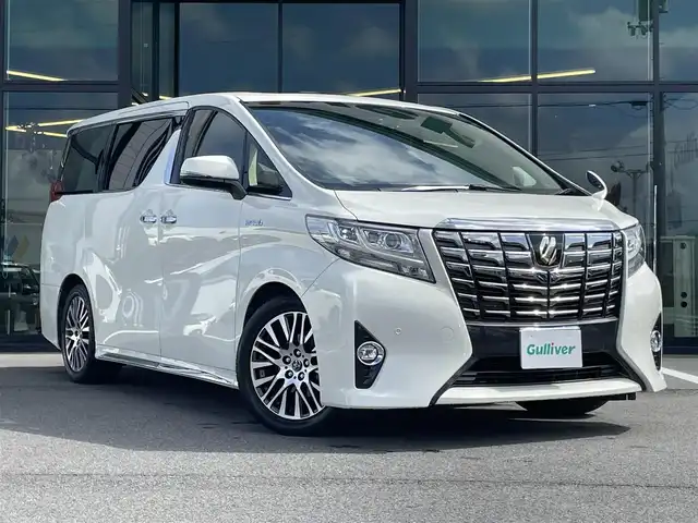 トヨタ アルファードハイブリット G Fパッケージ 愛媛県 2015(平27)年 9.8万km ラグジュアリーホワイトパールクリスタルシャインガラスフレーク 1オーナー/ツインサンルーフ/ALPINE専用10型ナビ【EX10】/　CD/DVD/Bluetooth/HDMI/フルセグTV/ガイド付きバックカメラ/ALPINE12.8型フリップダウンモニター/両側パワースライドドア/衝突被害軽減ブレーキ/クルーズコントロール/ステアリングヒーター/ベージュレザーシート/前席パワーシート(D席メモリー付)/前席シートヒーター/N席2列目オットマン/AC100Vアクセサリー/オートマチックハイビーム/オートライト/LEDヘッドライト/パワーバックドア/ビルトインETC/前後ドライブレコーダー/プッシュスタート/スペアキー×1/取説書