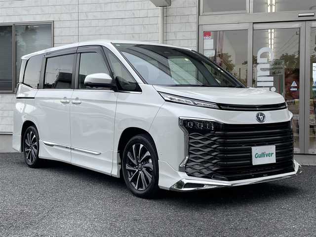 トヨタ ヴォクシー ハイブリッド S－Z 埼玉県 2023(令5)年 2万km ホワイトパールクリスタルシャイン ワンオーナー/メーカーオプションナビ(FM/AM/USB/BT/Wi-Fi/Miracast)/イモビライザー/デジタルミラー型ドラレコ/バックカメラ/アラウンドビューモニター/フリップダウンモニター/パーキングアシスト/サンシェード/オートライト/衝突軽減ブレーキ/電動格納ミラー/三列シート/シートヒーター(前・中シート)/両側スライドドア/オットマン/純正フロアマット/クルーズコントロール(追従)/横滑り防止/ISOFIX/ドアバイザー