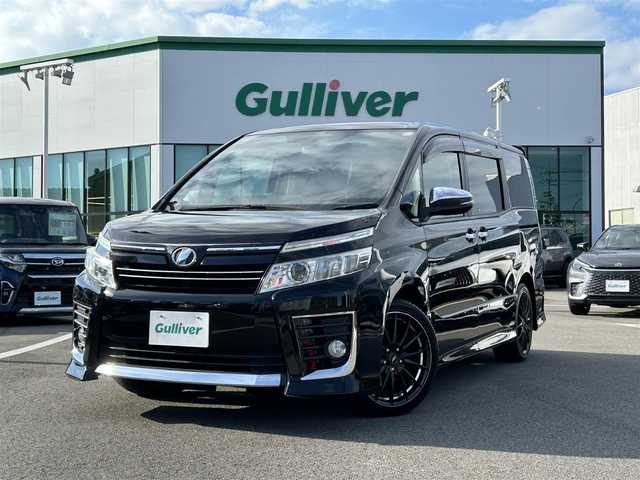 トヨタ ヴォクシー ZS 煌 愛媛県 2015(平27)年 7.7万km ブラック 登録時走行距離：76158km/メーカーオプション純正9inナビ/AM/FM/フルセグTV/Bluetooth/アルパインフリップダウンモニター/両側パワスラ/ビルトインETC/バックカメラ/追従クルコン/衝突軽減システム/横滑り防止装置/盗難防止装置/LEDヘッドライト/エンジンスタートボタン/スマートキー/スペアキー/社外アルミホイール/純正フロアマット