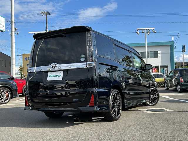 トヨタ ヴォクシー ZS 煌 愛媛県 2015(平27)年 7.7万km ブラック 登録時走行距離：76158km/メーカーオプション純正9inナビ/AM/FM/フルセグTV/Bluetooth/アルパインフリップダウンモニター/両側パワスラ/ビルトインETC/バックカメラ/追従クルコン/衝突軽減システム/横滑り防止装置/盗難防止装置/LEDヘッドライト/エンジンスタートボタン/スマートキー/スペアキー/社外アルミホイール/純正フロアマット