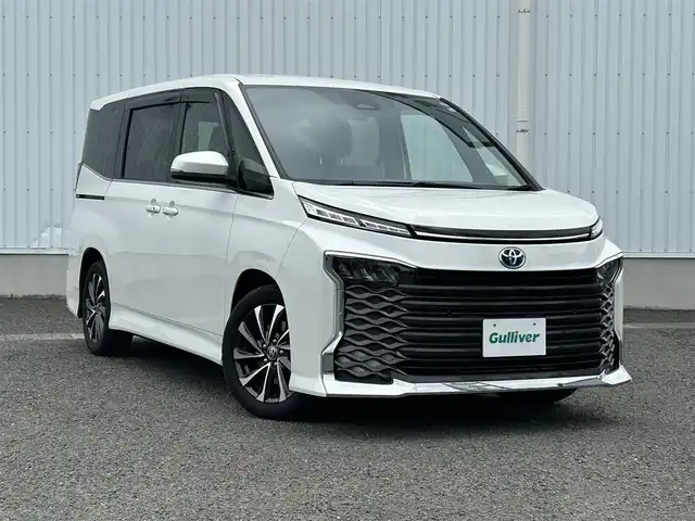 トヨタ ヴォクシー ハイブリッド 熊本県 2022(令4)年 0.9万km ホワイトパールクリスタルシャイン ディスプレイオーディオ/・AM/FM/USB/BT/HDMI/・フルセグTV/・CD/DVDキット/・バックカメラ/・後席モニター/トヨタセーフティーセンス/・プリクラッシュセーフティー/・レーンディパーチャーアラート/・ブラインドスポットモニター/・クリアランスソナー/・パーキングサポートブレーキ/・ロードサインアシスト/・レーダークルーズコントロール/・オートマチックハイビーム/両側パワースライドドア/パワーバックドア/前ドライブレコーダー/ビルトインETC２．０/革巻きステアリング/・ステアリングスイッチ/オートライト/・LEDライト/・フォグランプ/電動パーキング/・オートホールド/純正フロアマット/純正ドアバイザー/純正アルミホイール/スマートキー/・スペアキーｘ１