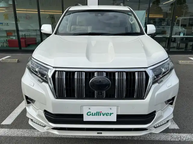 トヨタ ランドクルーザー プラド TX Lパッケージ 愛媛県 2023(令5)年 2.1万km ホワイトパールクリスタルシャイン 登録時走行距離：20800km/メーカーオプション純正メモリナビ/AM/FM/フルセグTV/Bluetooth/ETC/電動サードシート/パドルシフト/追従クルコン/レザーシート/シートヒーター/エアシート/衝突軽減システム/横滑り防止装置/盗難防止装置/レーンキープアシスト/LEDヘッドライト/オートライト/オートハイビーム/エンジンスタートボタン/スマートキー/スペアキー/純正アルミホイール/社外フロアマット