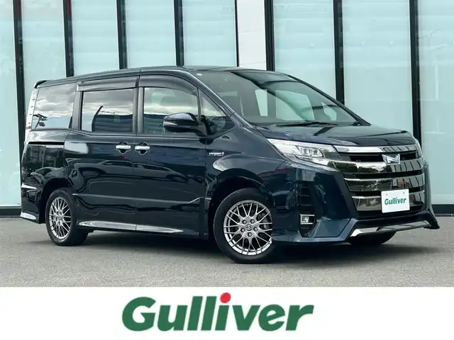 トヨタ ノア ハイブリッド Si ダブルバイビーⅡ 大阪府 2019(令1)年 3.3万km ブラッキッシュアゲハガラスフレーク 社外９インチナビ/   フルセグTV/CD/DVD/Bluetooth/USB/バックモニター/１０．１インチ後席モニター/（登録時走行距離 32629km）/衝突軽減ブレーキ/横滑り防止装置/前席シートヒーター/クルーズコントロール/両側パワースライドドア/ドライブレコーダー/ハーフレザーシート/オートマチックハイビーム/純正16インチアルミホイール/コーナーセンサー/プッシュスタート/スマートキー/ＥＴＣ/ＬＥＤライト