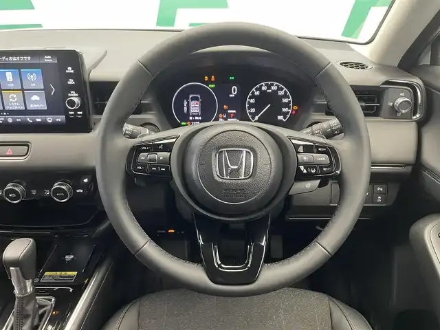 ホンダ ヴェゼル ハイブリッド e:HEV Z 鹿児島県 2025(令7)年 0.1万km未満 プラチナホワイトパール 禁煙車/ETC2.0/バックカメラ/メーカーナビ/（フルセグ/BT/AM・FM/USB/Android Auto/Apple Car Play）/ホンダセンシング/・衝突軽減ブレーキ/・前後誤発進抑制機能/・路外逸脱抑制機能/・標識認識機能/・先行車発進お知らせ機能/・車線逸脱防止支援システム/・踏み間違い衝突軽減システム/・アダクティブクルーズコントロール/・トラフィックジャムアシスト/・ブラインドスポットインフォメーション/置くだけ充電/電動リアゲート/シートヒーター/ステアリングヒーター/革巻きステアリング/ステアリングリモコン/ヒルディングアシスト/パドルシフト/電動パーキング/オートホールド/純正18インチAW/オートライト/フォグランプ/プッシュスタート/スマートキー/取扱説明書