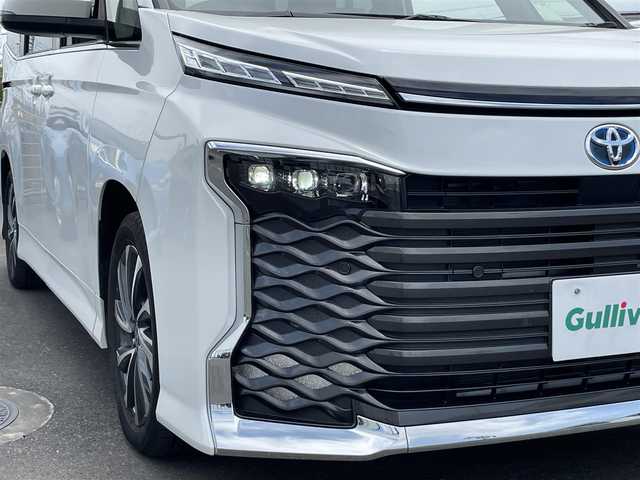 トヨタ ヴォクシー ハイブリッド S－Z 茨城県 2023(令5)年 0.9万km ホワイトパールクリスタルシャイン 純正ナビ/【AM・FM・TV・BT・USB・ＣＤ・ＤＶＤ】/快適利便パッケージHigh/ハンズフリーデュアルパワースライドドア（挟み込み防止機能付）/パワーバックドア（挟み込み防止機能・停止位置メモリー機能・パワーバックドアスイッチ〈車両サイド〉付）/ナノイーX/ステアリングヒーター/キャプテンシート追加機能：シートヒーター、オットマン（2WD車のみ）、角度調整付アームレスト（2WD車のみ）/電動リアゲート/両側パワスラ/BSM/HUD/デジタルインナーミラー/レーダークルコン/Ｂカメラ/ETC2.0/前方ドラレコ/前後コーナーセンサー/ブレーキホールド/100V電源