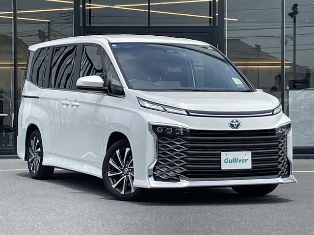 トヨタ ヴォクシー ハイブリッド S－Z 茨城県 2023(令5)年 0.9万km ホワイトパールクリスタルシャイン 純正ナビ/【AM・FM・TV・BT・USB・ＣＤ・ＤＶＤ】/快適利便パッケージHigh/ハンズフリーデュアルパワースライドドア（挟み込み防止機能付）/パワーバックドア（挟み込み防止機能・停止位置メモリー機能・パワーバックドアスイッチ〈車両サイド〉付）/ナノイーX/ステアリングヒーター/キャプテンシート追加機能：シートヒーター、オットマン（2WD車のみ）、角度調整付アームレスト（2WD車のみ）/電動リアゲート/両側パワスラ/BSM/HUD/デジタルインナーミラー/レーダークルコン/Ｂカメラ/ETC2.0/前方ドラレコ/前後コーナーセンサー/ブレーキホールド/100V電源