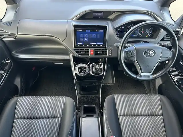 トヨタ ヴォクシー ハイブリッド ZS 煌 岡山県 2018(平30)年 9.9万km ホワイトパールクリスタルシャイン 登録時走行距離98348km/TRDエアロ/純正9インチナビ/フルセグTV(AM.FM.CD.DVD.TV.BT)/両側パワースライドドア/バックカメラ/ETC/シートヒーター/クリアランスソナー/衝突軽減ブレーキ/横滑り防止装置/クルーズコントロール/車線逸脱警報（レーンキープアシスト）/オートライト/オートマチックハイビーム/アイドリングストップ/16インチ純正AW/純正フロアマット/スペアキー/LEDヘッドライト/取扱説明書