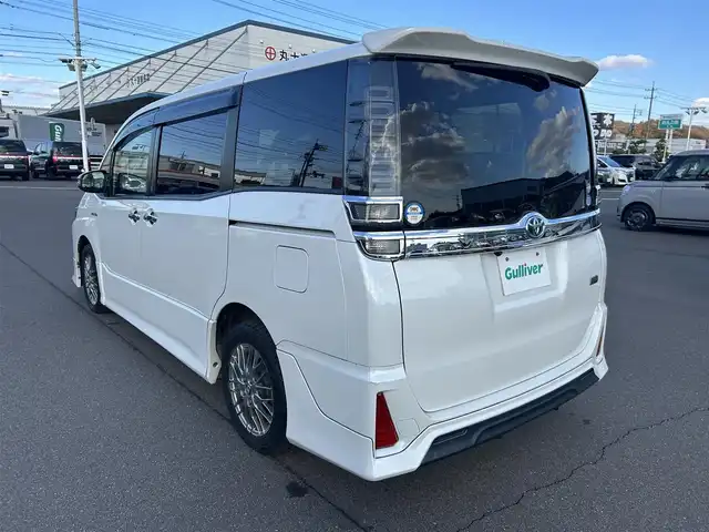 トヨタ ヴォクシー ハイブリッド ZS 煌 岡山県 2018(平30)年 9.9万km ホワイトパールクリスタルシャイン 登録時走行距離98348km/TRDエアロ/純正9インチナビ/フルセグTV(AM.FM.CD.DVD.TV.BT)/両側パワースライドドア/バックカメラ/ETC/シートヒーター/クリアランスソナー/衝突軽減ブレーキ/横滑り防止装置/クルーズコントロール/車線逸脱警報（レーンキープアシスト）/オートライト/オートマチックハイビーム/アイドリングストップ/16インチ純正AW/純正フロアマット/スペアキー/LEDヘッドライト/取扱説明書