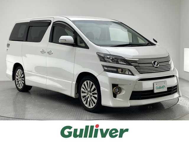 トヨタ ヴェルファイア 2．4Z ゴールデンアイズ 兵庫県 2013(平25)年 9.7万km ホワイトパールクリスタルシャイン ワンオーナー/ゴールデンアイズ専用装備/・専用18インチアルミホイール/・フロントフォグランプ（スモークメッキリング）/・プロジェクター式ヘッドランプリング（シャンパンゴールドリング）/・黒木目調パネル/プッシュスタート/MTモード付きAT/クルーズコントロール/コーナーセンサー/純正HDDナビ NHZN-X62G/フルセグTV/フリップダウンモニター/バックカメラ/ETC/両側パワースライドドア/パワーバックドア/レザー調シートカバー/HIDヘッドライト/オートライト/ドアバイザー