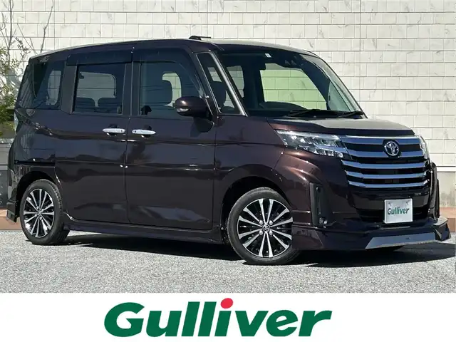 トヨタ ルーミー カスタムG－T 滋賀県 2023(令5)年 0.7万km プラムブラウンパールクリスタルシャイン モデリスタエアロ/両側パワースライドドア/9インチ純正ディスプレイオーディオ/（FM/AM/フルセグ/Bluetooth/USB）/バックカメラ/ETC/前後ドライブレコーダー/スマートアシスト/・ブレーキ制御付誤発進抑制機能/・衝突回避支援ブレーキ機能/・衝突警報機能/・レーンキープアシスト	/・アダプティブクルーズコントロール/・コーナー・バックセンサー（ソナー）	/・標識検知機能	/アイドリングストップ/電動格納ミラー/電子パーキング/ブレーキホールド/革巻きステアリング/ステアリングスイッチ/オートライト/LEDヘッドライト/フロントフォグ/フルオートエアコン/プッシュスタート/スマートキー/純正フロアマット/USB端子