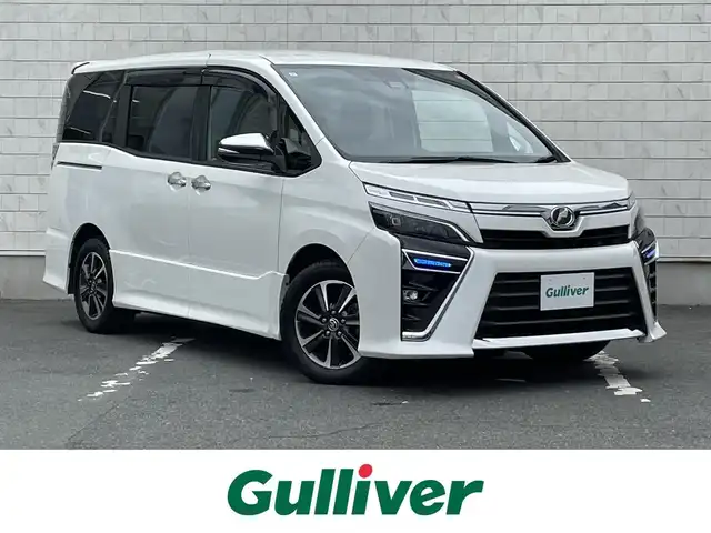 トヨタ ヴォクシー ZS 煌 愛知県 2019(平31)年 6.8万km ホワイトパールクリスタルシャイン ・純正SDメモリーナビ/・バックカメラ/・フルセグTV/・CD/DVD再生/・ETC（新セキュリティ対応）/・ミュージックサーバー（SD録音）/・Bluetooth接続/・3列シート/・両側パワースライドドア/・純正フロアマット/・純正16インチアルミホイール/・LEDヘッドライト/・オートマチックハイビーム/・コーナーセンサー（後方）/・横滑り防止装置/・衝突軽減ブレーキ/・レーンキープアシスト/・ドライブレコーダー（前）/・充電用USBポート（2個）/・MTモード付きAT/・クルーズコントロール/・全席オートエアコン/・モデリスタ シグネチャーイルミブレード