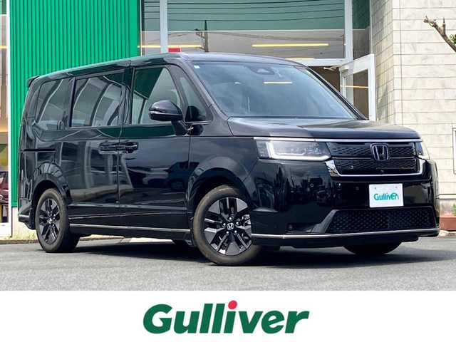 ホンダ ステップワゴン スパーダ eHEV 静岡県 2024(令6)年 0.5万km クリスタルブラックパール エンジンスタートボタン/パワーウィンドウ/パワーステアリング/パドルシフト/アイドリングストップ/スマートキー/スペアキー/Wオートエアコン/クルーズコントロール/ETC2.0/USB入力端子/全方位カメラ/純正11.4インチナビ（CD/DVD/BT/フルセグ）/三列シート/オットマン/電動リアゲート/純正ドライブレコーダー前後/ウォークスルー/純正フロアマット/純正アルミホイール/両側パワースライドドア/ハーフレザー/D席N席シートヒーター/ABS/横滑り防止装置/コーナーセンサー前後/レーンキープアシスト/オートライト/オートマチックハイビーム/LEDヘッドライト/W＋サイドエアバック/衝突軽減システム/カーテンエアバック/BSM/ホンダセンシング