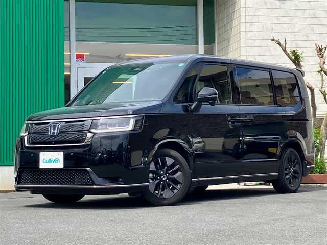 ホンダ ステップワゴン スパーダ eHEV 静岡県 2024(令6)年 0.5万km クリスタルブラックパール エンジンスタートボタン/パワーウィンドウ/パワーステアリング/パドルシフト/アイドリングストップ/スマートキー/スペアキー/Wオートエアコン/クルーズコントロール/ETC2.0/USB入力端子/全方位カメラ/純正11.4インチナビ（CD/DVD/BT/フルセグ）/三列シート/オットマン/電動リアゲート/純正ドライブレコーダー前後/ウォークスルー/純正フロアマット/純正アルミホイール/両側パワースライドドア/ハーフレザー/D席N席シートヒーター/ABS/横滑り防止装置/コーナーセンサー前後/レーンキープアシスト/オートライト/オートマチックハイビーム/LEDヘッドライト/W＋サイドエアバック/衝突軽減システム/カーテンエアバック/BSM/ホンダセンシング
