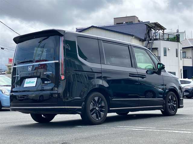 ホンダ ステップワゴン スパーダ eHEV 静岡県 2024(令6)年 0.5万km クリスタルブラックパール エンジンスタートボタン/パワーウィンドウ/パワーステアリング/パドルシフト/アイドリングストップ/スマートキー/スペアキー/Wオートエアコン/クルーズコントロール/ETC2.0/USB入力端子/全方位カメラ/純正11.4インチナビ（CD/DVD/BT/フルセグ）/三列シート/オットマン/電動リアゲート/純正ドライブレコーダー前後/ウォークスルー/純正フロアマット/純正アルミホイール/両側パワースライドドア/ハーフレザー/D席N席シートヒーター/ABS/横滑り防止装置/コーナーセンサー前後/レーンキープアシスト/オートライト/オートマチックハイビーム/LEDヘッドライト/W＋サイドエアバック/衝突軽減システム/カーテンエアバック/BSM/ホンダセンシング