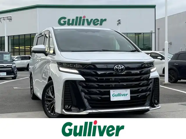 トヨタ ヴェルファイア ハイブリット Z プレミア 愛媛県 2023(令5)年 0.9万km プラチナホワイトパールマイカ 登録時走行距離：9038Km/メーカーオプション純正14インチHDナビ/AM/FM/フルセグTV/Bluetooth/ビルトインＥＴＣ2.0/後席モニター/全周囲カメラ/前後ドライブレコーダー/両側パワスラ/電動リアゲート/ワイヤレス充電/パドルシフト/追従クルコン/革シート/デジタルミラー/横滑り防止装置/パーキングアシスト/LEDヘッドライト/オートライト/オートハイビーム/フォグランプ/エンジンスタートボタン/スマートキー/純正アルミホイール/純正フロアマット/シートーヒーター/エアシート/シートメモリ