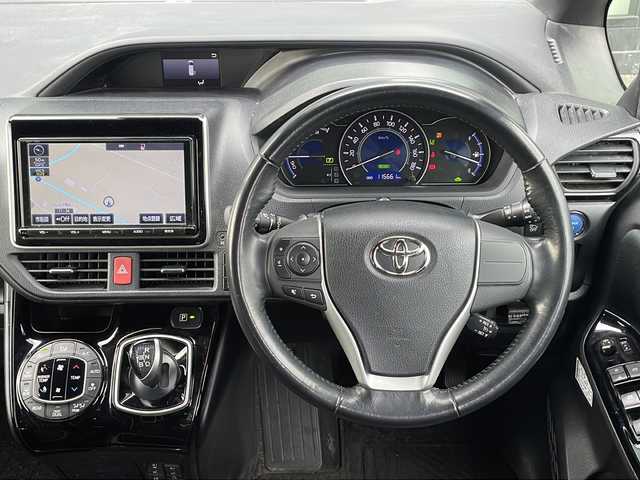 トヨタ ノア ハイブリッド Si 香川県 2018(平30)年 11.6万km ブラッキッシュアゲハガラスフレーク Toyota Safety Sense C/・プリクラッシュセーフティシステム（PCS）/・レーンディパーチャーアラート（LDA）/・オートマチックハイビーム（AHB）/・先行車発進告知機能/純正9型メモリナビ(NSZT-Y66T)/・フルセグTV/・AM/FM/・DVD/CD/・Bluetooth接続/後席モニター（V12T-R66C）/両側パワースライドドア/バックカメラ/パーソナルテーブル/ロールカーテンシェード/純正16インチアルミホイール/純正LEDライト/フロントフォグランプ/横滑り防止機能/レーダークルーズコントロール/前席シートヒーター/前席エアシート/プッシュスタート/スマートキー/ステアリングリモコン/純正フロアマット/ETC/前後ドライブレコーダー/ウィンカーミラー