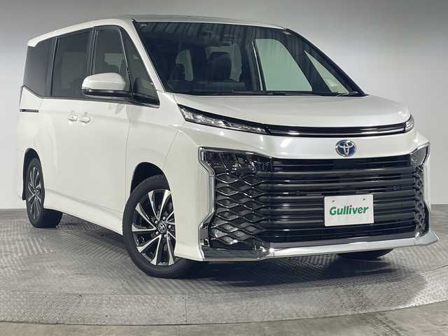 トヨタ ヴォクシー ハイブリッド S－Z 神奈川県 2025(令7)年 0.1千km ホワイトパールクリスタルシャイン 登録済未使用車/ディスプレイオーディオプラス/純正10.5型ディスプレーオーディオ/メモリーナビ/フルセグ　CD DVD USB　HDMI　Miracast　Bluetooth　Applecarplay　Androidauto　ETC2.0/バックカメラ/両側電動スライドドア/パワーバックドア/ドライビングサポートパッケージ/快適利便パッケージ/セーフティセンス/プリクラッシュセーフティ/レーンディパーチャーアラート/オートマチックハイビーム/ドライバー異常時対応システム/発進遅れ告知機能/レーントレーシングアシスト/レーダークルーズコントロール/ロードサインアシスト/パーキングサポートブレーキ/車両接近通報装置/プロアクティブドライビングアシスト/カラーヘッドアップディスプレイ/デジタルインナーミラー/ナノイーX/ステアリングヒーター/前席/2列目左右シートヒーター/ステアリングヒーター/合皮/ファブリックコンビシート/革巻きステアリング/AC100V/SOSコール/プッシュスタート/スマートキー/LEDヘッドライト/オートライト/純正17インチアルミホイール/純正サイド/リアスポイラー