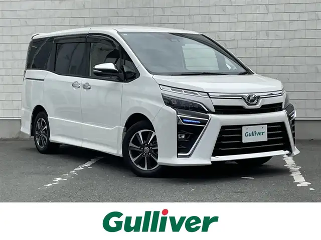 トヨタ ヴォクシー ZS 煌Ⅱ 愛知県 2019(令1)年 2万km ホワイトパールクリスタルシャイン ・純正SDメモリーナビ/・バックカメラ/・フルセグTV/・CD/DVD再生/・ETC（新セキュリティ対応）/・Bluetooth/USB/IWCH接続/・3列シート/・両側パワースライドドア/・社外製フロアマット/・ウォークスルー（1列目）/・純正16インチアルミホイール/・LEDヘッドライト/・オートマチックハイビーム/・コーナーセンサー（後方）/・横滑り防止装置/・衝突軽減ブレーキ/・レーンキープアシスト/・ドライブレコーダー（前）/・充電用USBポート（2個）/・クルーズコントロール/・MTモード付きAT/・全席オートエアコン/・カロッツェリアスピーカー/・モデリスタ シグネチャーイルミブレード