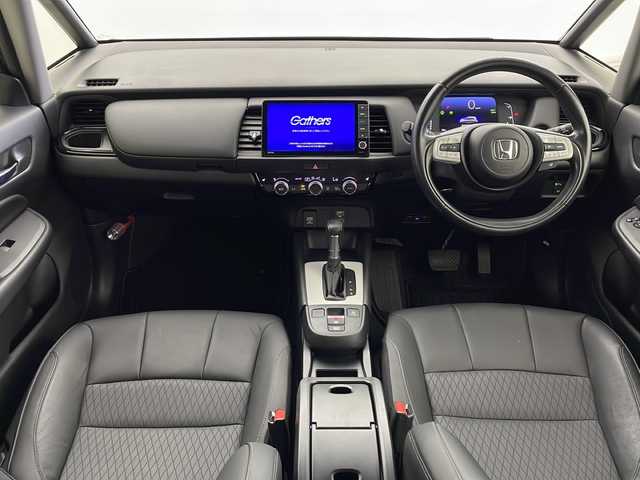 ホンダ フィット e:HEVリュクス 鹿児島県 2020(令2)年 1.8万km シャイニンググレーM ホンダセンシング　/●衝突軽減ブレーキ〈CMBS〉/●誤発進抑制機能/●後方誤発進抑制機能/●近距離衝突軽減ブレーキ/●歩行者事故低減ステアリング/●路外逸脱抑制機能/●渋滞追従機能付アダプティブ・クルーズ・コントロール〈ACC〉/●車線維持支援システム〈LKAS〉/●先行車発進お知らせ機能●標識認識機能/●オートハイビーム/純正９型ナビ　/前後ドライブレコーダー　/電子パーキング　/オートホールド　/ハンドルヒーター　/フォグライト　/LEDヘッドライト/ドアバイザー　/ウインカーミラー　/シートヒーター/ワイヤレス充電器/純正アルミホイール