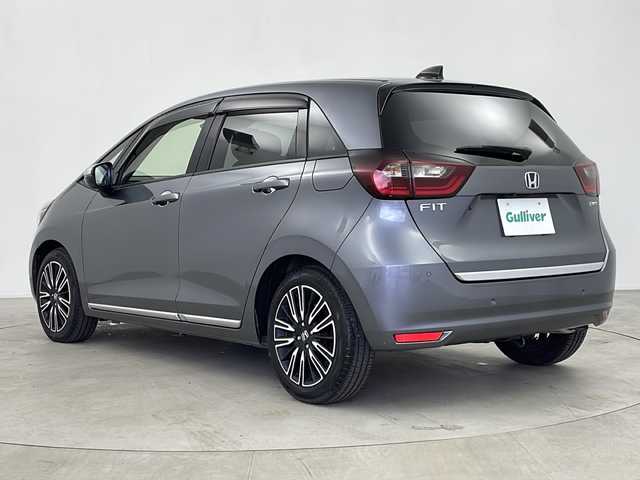 ホンダ フィット e:HEVリュクス 鹿児島県 2020(令2)年 1.8万km シャイニンググレーM ホンダセンシング　/●衝突軽減ブレーキ〈CMBS〉/●誤発進抑制機能/●後方誤発進抑制機能/●近距離衝突軽減ブレーキ/●歩行者事故低減ステアリング/●路外逸脱抑制機能/●渋滞追従機能付アダプティブ・クルーズ・コントロール〈ACC〉/●車線維持支援システム〈LKAS〉/●先行車発進お知らせ機能●標識認識機能/●オートハイビーム/純正９型ナビ　/前後ドライブレコーダー　/電子パーキング　/オートホールド　/ハンドルヒーター　/フォグライト　/LEDヘッドライト/ドアバイザー　/ウインカーミラー　/シートヒーター/ワイヤレス充電器/純正アルミホイール