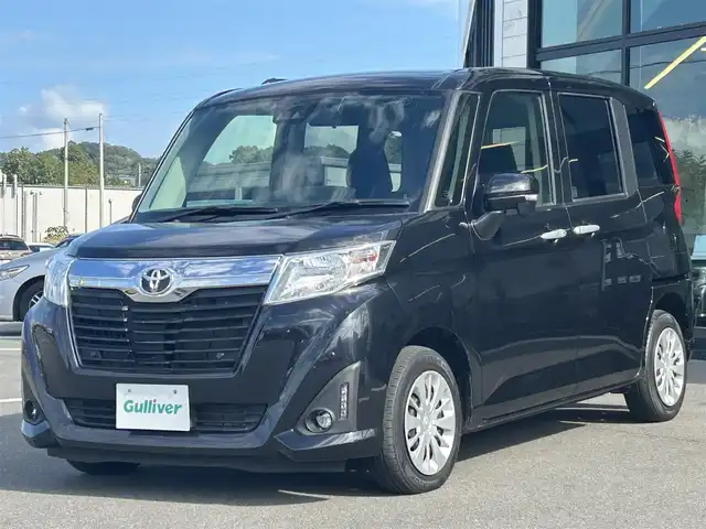 トヨタ ルーミー G－T 愛媛県 2020(令2)年 2.6万km ブラックマイカメタリック 純正9型ナビ/純正12.1型フリップダウンモニター/両側パワースライドドア/純正ドライブレコーダー/バックカメラ/クルーズコントロール/アイドリングストップ/衝突被害軽減装置/車線逸脱防止装置/クリアランスソナー/ステアリングリモコン/後席サンシェイド/電動格納ミラー/ヘッドライトレベライザー/シガーソケット/純正ホイールキャップ/現状サマー(鉄)(165/65/R14)/DUNLOP ENASAVE EC300+/禁煙車