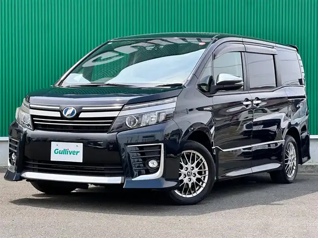 トヨタ ヴォクシー ハイブリッド ZS 煌Ⅱ 宮城県 2016(平28)年 9.5万km ブラッキッシュアゲハガラスフレーク セーフティセンスC/・プリクラッシュセーフティ/・レーンディパーチャーアラート/・オートマチックハイビーム/・先行車発進告知/純正12インチフリップダウンモニター（V12T-R66C）/純正10インチナビ（ZSZN-Z66T）/・CD/DVD/・Bluetooth/・フルセグTV/バックカメラ/ビルトインETC2.0/ドライブレコーダー/両側パワースライドドア/革巻きステアリング/ステアリングスイッチ/LEDヘッドランプ/フォグランプ/オートライト/スマートキー＆プッシュスタート/電動格納ミラー/純正16インチAW/純正フロアマット/純正ドアバイザー/Wエアバッグ