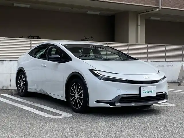 トヨタ プリウス Z 大阪府 2023(令5)年 1.3万km プラチナホワイトパールマイカ ワンオーナー/OP:純正12.3インチディスプレイオーディオPlus/　（コネクティッドナビ対応）/　・フルセグTV（走行中視聴可能）/　・AppleCarPlay/　・AndroidAuto/　・FM/AM/Bluetooth/USB/OP：純正デジタルインナーミラー/OP:純正ナビ連動型前後ドライブレコーダー/パノラミックビューモニター/ETC2.0/レザーシート/運転席パワーシート（メモリー機能付き）/前席シートヒーター・エアシート/ステアリングヒーター/ステアリングスイッチ/社外17インチアルミホイール/ToyotaSafetySense/　・プリクラッシュセーフティ/　・緊急時操舵支援＋FCTA＋LCA/　・LTA＋LDA/　・レーダークルーズコントロール（全車速追従機能付き）/　・オートマチックハイビーム/　・ロードサインアシスト/　・ドライバー異常時対応システム/　・プロアクティブドライビングアシスト/　・発進遅れ告知機能/　・BSM＋SEA＋後方車両接近告知＋周辺車両接近時サポート＋後方車両への接近警報＋セカンダリーコリジョンブレーキ