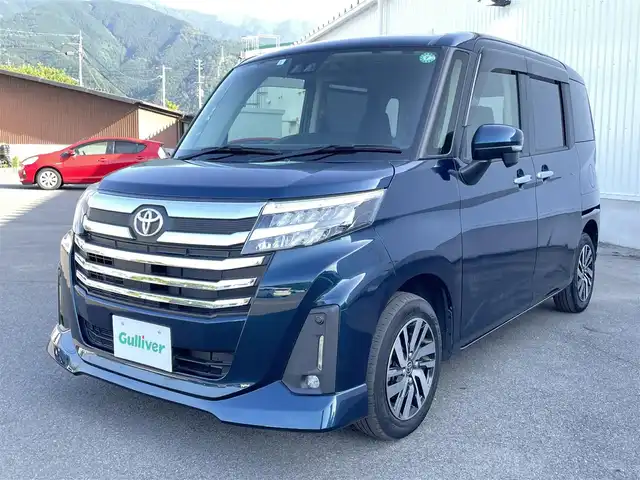 トヨタ ルーミー カスタムG 愛媛県 2023(令5)年 1.8万km レーザーブルークリスタルシャイン スマートアシスト/衝突回避支援ブレーキ/車線逸脱警報/ブレーキ制御付御発進抑制機能/アダプティブクルーズコントロール/先行車発進お知らせ機能/ふらつき警報/路外逸脱警報/標識認識機能/社外7インチナビ【AVN-R10W】/　CD/DVD/Bluetooth/フルセグTV/ビルトインETC/両側パワースライドドア/オートライト/LEDヘッドライト/フロントフォグ/革巻きステアリング/電子パーキングブレーキ/フロアマット/ドアバイザー