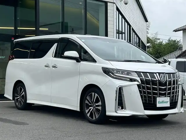 トヨタ アルファード S Cパッケージ 愛媛県 2021(令3)年 1.8万km ホワイトパールクリスタルシャイン 純正ナビ（Bluetooth/フルセグTV）/レーダークルーズコントロール/前後ドライブレコーダー/バックカメラ/USB入力端子/100V充電/三列シート/パワーシート/ステアリングヒーター/シートヒーター/エアシート/サンルーフ/オットマン/電動リアゲート/両側パワースライドドア/純正フロアマット/純正アルミホイール/前後コーナーセンサー/LEDヘッドライト/オートマチックハイビーム
