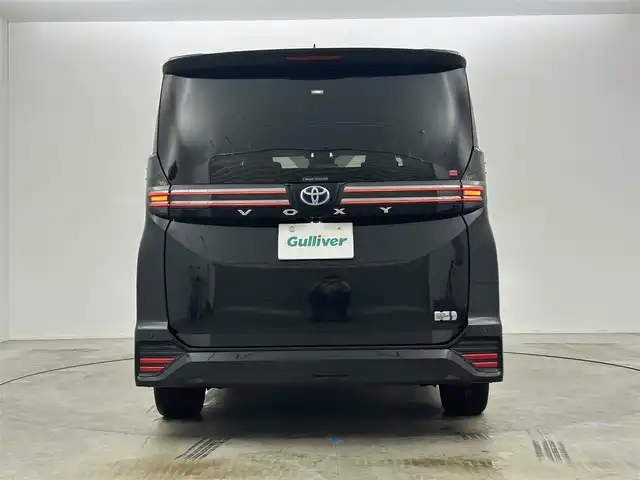 トヨタ ヴォクシー ハイブリッド S－Z 岡山県 2024(令6)年 1.9万km グリッターブラックガラスフレーク 快適利便パッケージ/ハーフレザーシート/純正10.5インチディスプレイオーディオ/　「ナビ/フルセグ/Bluetooth/DVD/ Carplay」/ブラインドスポットモニター/バックカメラ/ユニバーサルステップ（左回りのみ）/追従型クルーズコントロール/オートハイビーム/LEDヘッドライト/ビルトインETC2.0/両側パワースライドドア/シートヒーター(1列目/2列目)/衝突軽減ブレーキシステム/車線逸脱防止システム/横滑り防止装置/純正17インチアルミホイール/コーナーセンサー（前後）/純正フロアマット/ステアリングスイッチ/プッシュスタート/スマートキー×1