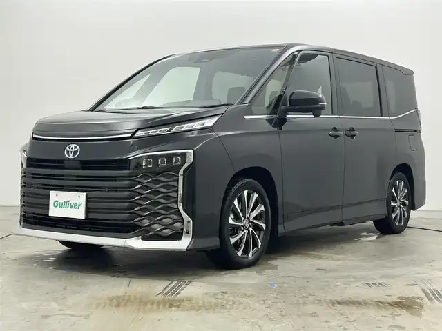 トヨタ ヴォクシー ハイブリッド S－Z 岡山県 2024(令6)年 1.9万km グリッターブラックガラスフレーク 快適利便パッケージ/ハーフレザーシート/純正10.5インチディスプレイオーディオ/　「ナビ/フルセグ/Bluetooth/DVD/ Carplay」/ブラインドスポットモニター/バックカメラ/ユニバーサルステップ（左回りのみ）/追従型クルーズコントロール/オートハイビーム/LEDヘッドライト/ビルトインETC2.0/両側パワースライドドア/シートヒーター(1列目/2列目)/衝突軽減ブレーキシステム/車線逸脱防止システム/横滑り防止装置/純正17インチアルミホイール/コーナーセンサー（前後）/純正フロアマット/ステアリングスイッチ/プッシュスタート/スマートキー×1