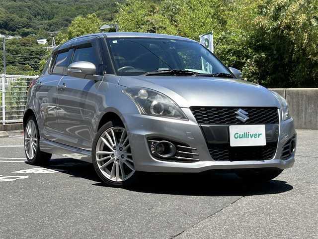 スズキ スイフト スポーツ 長崎県 2013(平25)年 5.1万km プレミアムシルバーメタリック 社外HDDナビ(FM/AM/BT/CD/DVD)/プッシュスタート/スマートキー/スペアキー(1本)/追従機能無しクルーズコントロール/ETC/バックカメラ/MTモード付AT/パドルシフト/ステアリングリモコン/前方ドラレコ/MonsterSport マフラー/ペダルカバー/フロアマット/純正17インチアルミホイール/ABS/ESP/オートライト/SRSダブルエアバッグ/フォグランプスイッチ/取扱説明書/保証書/記録簿/ナビ取扱説明書