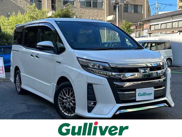 トヨタ ノア ハイブリッド Si ダブルバイビー 埼玉県 2018(平30)年 8.4万km ホワイトパールクリスタルシャイン 登録時84070km/ワンオーナー/純正メモリナビ（NSZN-Z68T）/フルセグ/CD/DVD/BT/バックカメラ/衝突被害軽減ブレーキ/レーンキープアシスト/横滑り防止装置/クルーズコントロール/純正フリップダウンモニター（V12T-R68C）/EV MODE/ECO MODE/PWR MODE/ドライブレコーダー（ZDR-013）/ビルトインETC2.0/シートヒーター（D＋N席）/両側パワースライドドア/プッシュスタート/オートライト/オートマチックハイビーム/電動格納ミラー/ウィンカーミラー/革巻きハンドル/純正フロアマット/LEDヘッドライト/フォグ/純正16インチアルミホイール/ドアバイザー/スマートキー×2/保証書/取説/ナビ取説