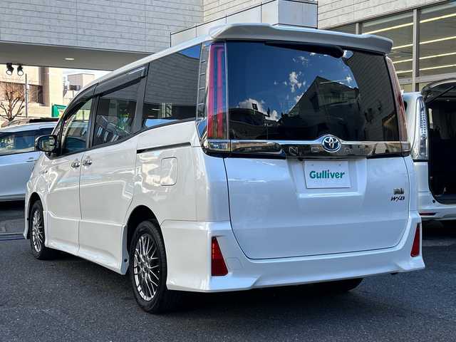 トヨタ ノア ハイブリッド Si ダブルバイビー 埼玉県 2018(平30)年 8.4万km ホワイトパールクリスタルシャイン 登録時84070km/ワンオーナー/純正メモリナビ（NSZN-Z68T）/フルセグ/CD/DVD/BT/バックカメラ/衝突被害軽減ブレーキ/レーンキープアシスト/横滑り防止装置/クルーズコントロール/純正フリップダウンモニター（V12T-R68C）/EV MODE/ECO MODE/PWR MODE/ドライブレコーダー（ZDR-013）/ビルトインETC2.0/シートヒーター（D＋N席）/両側パワースライドドア/プッシュスタート/オートライト/オートマチックハイビーム/電動格納ミラー/ウィンカーミラー/革巻きハンドル/純正フロアマット/LEDヘッドライト/フォグ/純正16インチアルミホイール/ドアバイザー/スマートキー×2/保証書/取説/ナビ取説