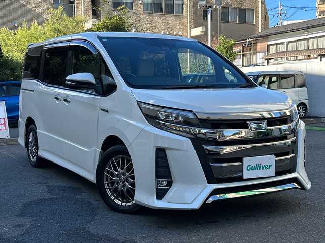 トヨタ ノア ハイブリッド Si ダブルバイビー 埼玉県 2018(平30)年 8.4万km ホワイトパールクリスタルシャイン 登録時84070km/ワンオーナー/純正メモリナビ（NSZN-Z68T）/フルセグ/CD/DVD/BT/バックカメラ/衝突被害軽減ブレーキ/レーンキープアシスト/横滑り防止装置/クルーズコントロール/純正フリップダウンモニター（V12T-R68C）/EV MODE/ECO MODE/PWR MODE/ドライブレコーダー（ZDR-013）/ビルトインETC2.0/シートヒーター（D＋N席）/両側パワースライドドア/プッシュスタート/オートライト/オートマチックハイビーム/電動格納ミラー/ウィンカーミラー/革巻きハンドル/純正フロアマット/LEDヘッドライト/フォグ/純正16インチアルミホイール/ドアバイザー/スマートキー×2/保証書/取説/ナビ取説