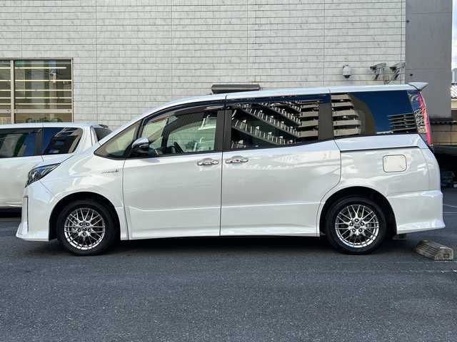 トヨタ ノア ハイブリッド Si ダブルバイビー 埼玉県 2018(平30)年 8.4万km ホワイトパールクリスタルシャイン 登録時84070km/ワンオーナー/純正メモリナビ（NSZN-Z68T）/フルセグ/CD/DVD/BT/バックカメラ/衝突被害軽減ブレーキ/レーンキープアシスト/横滑り防止装置/クルーズコントロール/純正フリップダウンモニター（V12T-R68C）/EV MODE/ECO MODE/PWR MODE/ドライブレコーダー（ZDR-013）/ビルトインETC2.0/シートヒーター（D＋N席）/両側パワースライドドア/プッシュスタート/オートライト/オートマチックハイビーム/電動格納ミラー/ウィンカーミラー/革巻きハンドル/純正フロアマット/LEDヘッドライト/フォグ/純正16インチアルミホイール/ドアバイザー/スマートキー×2/保証書/取説/ナビ取説