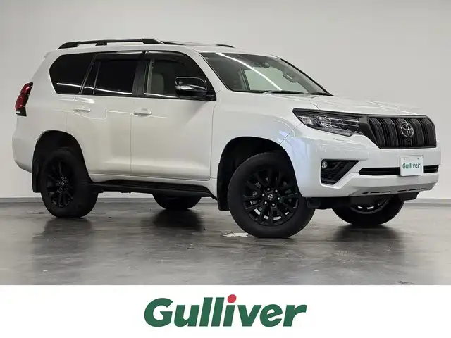 トヨタ ランドクルーザー プラド TX Lパッケージ マットブラED 三重県 2024(令6)年 1.4万km ホワイトパールクリスタルシャイン 2.8L ディーゼルターボ/4WD/MTモード付フロア6AT/【OP】純正 9インチナビ/（AM/FM/USB/iPod/Bluetooth/Miracast/CarPlay/AndroidAuto）/【OP】マルチテレインモニター（360カメラ）/ドライブレコーダー前後/ビルトイン ETC2.0/Toyota Safety Sense/・プリクラッシュセーフティ［PCS］/・レーンディパーチャーアラート［LDA］/・レーダークルコン/・オートハイビーム［AHB］/・ロードサインアシスト［RSA］/・【OP】ブラインドスポットモニター［BSM］＆パーキングサポートブレーキ（前後静止物・後方接近車両）/・先行車発進告知機能［TMN］/・オートハイビーム［AHB］/・ダウンヒルアシストコントロール*/装備/・【OP】ムーンルーフ/ブラックルーフレール/・本革シート（ニュートラルベージュ）/・シートヒーター＆ベンチレーション（D/N）/・左右独立オートエアコン/・オートライト＆ハイビーム/・LED ヘッドランプ＋フロントフォグランプ/・センターデフロック*/・2速発進機能*/・DPF手動再生機能*/・マットブラED専用 純正18inAW/・保/取/ナビ取/・スマートキーx2/など/*…ディーゼルのみの装備