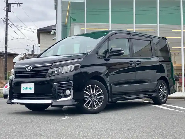 トヨタ ヴォクシー ZS 静岡県 2015(平27)年 5.3万km ブラック エンジンスタートボタン/パワーステアリング/パワーウィンドウ/アイドリングストップ/スマートキー/スペアキー/Wオートエアコン/フリップダウンモニター/ETC/バックカメラ/9インチナビ(CD/DVD/BT/フルセグ)/3列シート/チップアップシート/純正フロアマット/左側パワースライドドア/右側スライドドア/純正アルミホイール/ABS/横滑り防止装置/オートライト/LEDヘッドライト/Wエアバック
