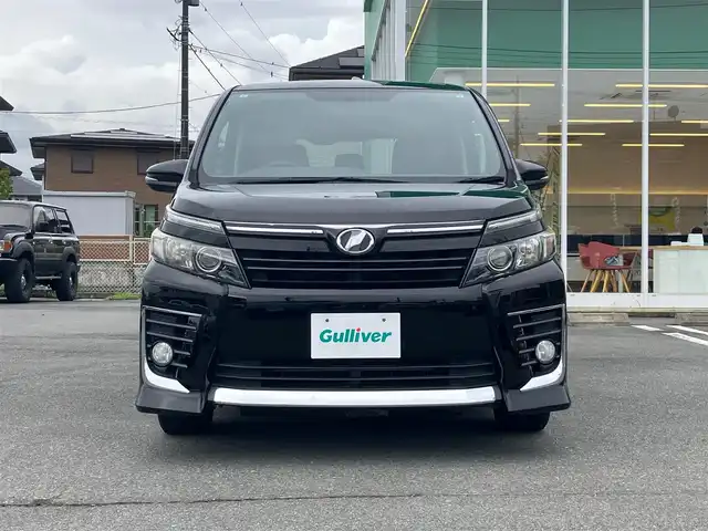 トヨタ ヴォクシー ZS 静岡県 2015(平27)年 5.3万km ブラック エンジンスタートボタン/パワーステアリング/パワーウィンドウ/アイドリングストップ/スマートキー/スペアキー/Wオートエアコン/フリップダウンモニター/ETC/バックカメラ/9インチナビ(CD/DVD/BT/フルセグ)/3列シート/チップアップシート/純正フロアマット/左側パワースライドドア/右側スライドドア/純正アルミホイール/ABS/横滑り防止装置/オートライト/LEDヘッドライト/Wエアバック