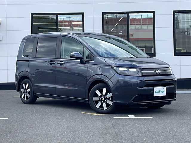 ホンダ フリード ハイブリット e:HEV AIR EX 山口県 2025(令7)年 0.1千km メテオロイドグレーメタリック 純正9インチナビ(LXM-242ZFNI)/【Bluetooth/フルセグTV/Apple CarPlay/Android Auto】/ホンダセンシング/・衝突軽減ブレーキ（CMBS）/・先行車発進お知らせ機能/・歩行者事故低減ステアリング/・路外逸脱抑制機能/・標識認識機能/・渋滞追従機能付アダプティブクルーズコントロール/・車線維持支援システム（LKAS）/・トラフィックジャムアシスト（渋滞運転支援機能）/・ブラインドスポットインフォメーション/・誤発進抑制機能/・後方誤発進抑制機能/・近距離衝突軽減ブレーキ/・急アクセル抑制機能/・パーキングセンサーシステム/・後退出庫サポート/・オートハイビーム/・アダプティブドライビングビーム/両側パワースライドドア/バックカメラ/LEDヘッドライト/D/Nシートヒーター/プッシュスタート/スマートキー/ステアリングリモコン