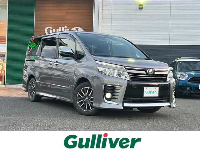 トヨタ ヴォクシー ZS 煌 佐賀県 2015(平27)年 9.7万km アイスチタニウムマイカメタリック エンジンスタートボタン/保証書/取扱説明書/記録簿/MTモード付AT/アイドリングストップ/スマートキー/スペアキー有/Bluetooth接続/後席用モニター/CD再生/USB入力端子/ビルトインETC/バックカメラ/ワンセグTV/メモリナビ/３列シート/前後ドライブレコーダー/ウォークスルー/両側パワースライドドア/ABS/純正アルミホイール/レーンキープアシスト/オートライト/LEDライト/革巻ステアリング/ステアリングスイッチ