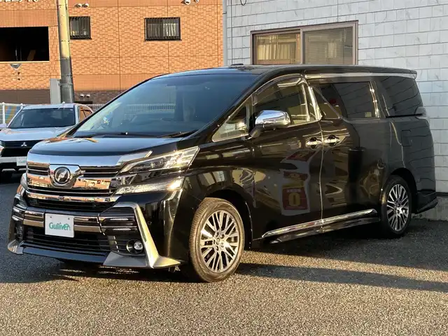 トヨタ ヴェルファイア Z Gエディション 福岡県 2015(平27)年 7.4万km ブラック モデリスタエアロ(リア)/フロントガーニッシュ/ツインムーンルーフ/純正10.1インチフリップダウンモニター/JBLプレミアムサウンド/純正9インチメーカーナビ/(AM/FM/CD/DVD/Bluetooth/フルセグTV)/全方位カメラ/バック/フロント/サイドカメラ/運転支援/・プリクラッシュセーフティシステム/・クリアランスソナー/・レーダークルーズコントロール/横滑り防止/純正18インチアルミホール/両側パワースライドドア/パワーバックドア/純正LEDスタイリッシュビーム(フロントガーニッシュ用)/黒レザーシート/レーダー探知機【ASSURA AR-W51GA】/ビルトインETC/純正インテリアイルミネーション/純正スカッフイルミネーション/ステアリングヒーター/革巻きステアリング/ステアリングスイッチ/パワーシート(D/N)/シートヒーター(D/N)/シートメモリー(D)/オットマン(N/セカンドシート)/後席電動サンシェード/純正フロアマット/ナノイー/ドアバイザー/ブレーキホールド/プッシュスタート/USBポート/スペアキー×1/100V電源/ISOFIX/保証書/取説、ナビ取説