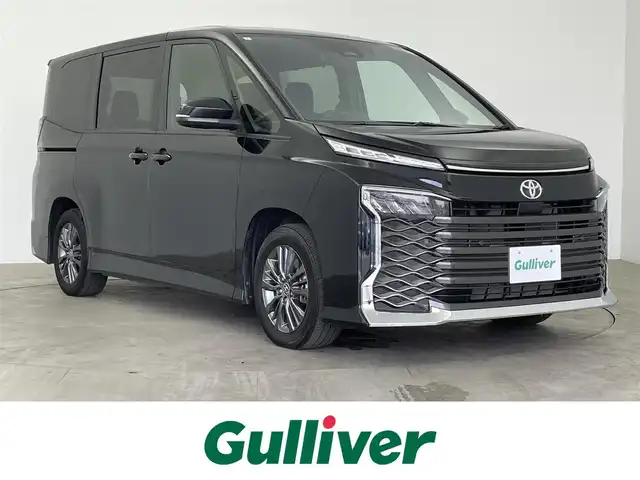 トヨタ ヴォクシー S－G 大分県 2024(令6)年 1.6万km アティチュードブラックマイカ 純正ディスプレイオーディオ/（AM/FM/Bluetooth）/バックカメラ/コーナーセンサー（前後）/レーンキープアシスト/横滑り防止装置/衝突軽減システム/カーテンエアバッグ/ブレーキホールド/アダクティブクルーズコントロール/片側パワースライドドア/LEDヘッドライト/オートライト/オートマチックハイビーム/ビルトインETC2.0/MTモード付AT/純正16インチアルミホイール/純正フロアマット/スマートキー/スペアキー1本