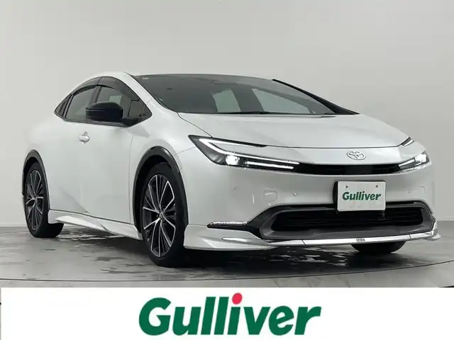 トヨタ プリウス Z 熊本県 2024(令6)年 2.2万km プラチナホワイトパールマイカ ワンオーナー/モデリスタエアロ/純正12.3インチディスプレイ(TV・ナビ機能付)/・AM/FM/USB/Bluetooth/パノラミックビューモニター/ビルトインETC2.0/アドバンストパーク/TVキャンセラー/パワーバックドア/電子パーキングブレーキ/AUTO HOLD機能/100V電源/置くだけ充電/DN席シートヒーター/シートベンチレーション/ISOFIX対応/革巻きステアリング/ステアリングヒーター/ステアリングリモコン/純正19インチアルミホイール/純正LEDヘッドライト/・オートマチックハイビーム/純正フロアマット/純正ドアバイザー/新車保証書/スペアキー１本/トヨタセーフティセンス/・レーダークルーズコントロール/・レーンディパーチャーアラート/・ブラインドスポットモニター/・プリクラッシュセーフティ/・クリアランスソナー/・プロアクティブドライビングアシスト/・リヤクロストラフィックアラート/・後方車両接近告知/・リヤカメラディテクション/・パーキングサポートブレーキ/・安心降車アシスト/・周辺車両接近時サポート/・ロードサインアシスト
