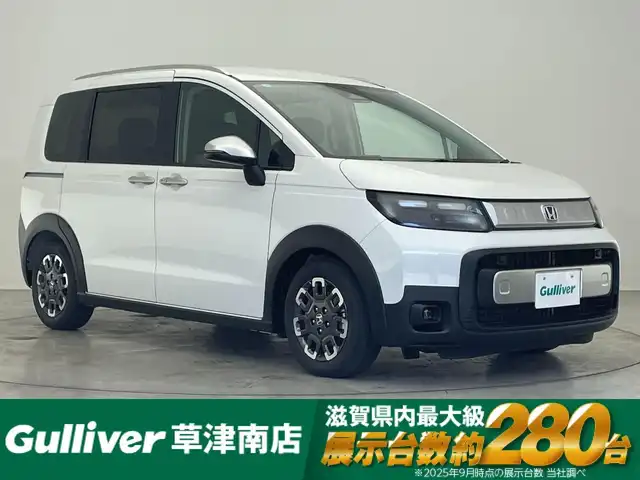 ホンダ フリード ハイブリット e:HEV クロスター 滋賀県 2025(令7)年 0.1千km プラチナホワイトパール 登録済未使用車/純正9インチナビ/【Bluetooth/フルセグTV/Apple CarPlay/Android Auto】/ホンダセンシング/・衝突軽減ブレーキ（CMBS）/・先行車発進お知らせ機能/・歩行者事故低減ステアリング/・路外逸脱抑制機能/・標識認識機能/・渋滞追従機能付アダプティブクルーズコントロール/・車線維持支援システム（LKAS）/・トラフィックジャムアシスト（渋滞運転支援機能）/・ブラインドスポットインフォメーション/・誤発進抑制機能/・後方誤発進抑制機能/・近距離衝突軽減ブレーキ/・急アクセル抑制機能/・パーキングセンサーシステム/・後退出庫サポート/・オートハイビーム/・アダプティブドライビングビーム/両側パワースライドドア/電動パーキングブレーキ/オートブレーキホールド/プッシュスタート/スマートキー/ステアリングリモコン