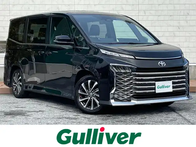 トヨタ ヴォクシー S－Z 滋賀県 2023(令5)年 1.8万km グリッターブラックガラスフレーク 両側パワースライドドア/純正10.5インチナビ/（AM/FM/CD/DVD/フルセグ/Bluetooth/USB）/バックカメラ/前後ドライブレコーダー/ビルトインETC2.0/トヨタセーフティセンス/・踏み間違い防止アシスト/・ブレーキアシスト/・プリクラッシュブレーキアシスト/・ヒルスタート（坂道発進）アシスト/・前方衝突防止支援システム/・TCS（トラクションコントロールシステム）/・VDC（ビークルダイナミクスコントロール）/・レーンキープアシスト/・車間自動制御システム/・ASCD（オートスピードコントロール装置）/・ABS（アンチロックブレーキシステム）/・バックビューモニター/・標識検知機能/電動格納ウインカーミラー/電子パーキング/ブレーキホールド/ステアリングスイッチ/革巻きステアリング/オートライト/オートハイビーム/LEDヘッドライト/フロントフォグ/フルオートエアコン/プッシュスタート/スマートキー/サンシェード/フロアマット